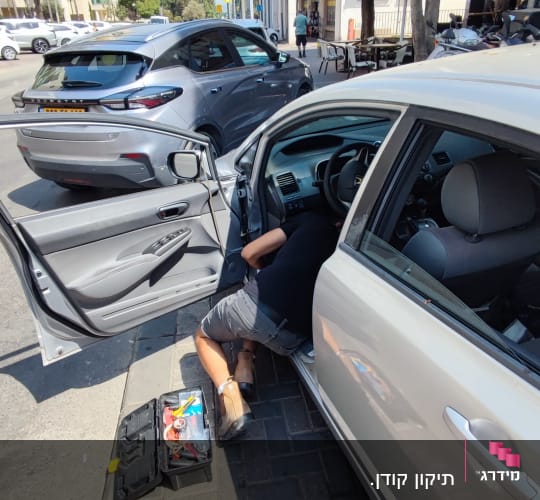 אדם מתקן רכב עם ארגז כלים פתוח